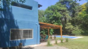 una casa azul con pérgola junto a una piscina en El techo en Zelaya