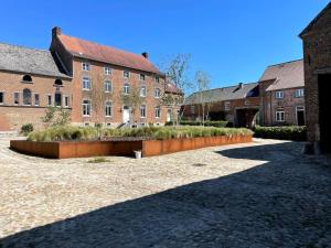 un gran edificio de ladrillo con un patio delante de él en Cottage entier : 6 à 8 personnes - La Ferme du Try en Frasnes-lez-Gosselies