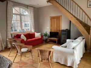 uma sala de estar com um sofá vermelho e cadeiras em Cottage entier : 6 à 8 personnes - La Ferme du Try em Frasnes-lez-Gosselies