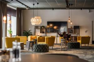 a room with yellow chairs and tables and a tv at Hotell Kramm in Kramfors