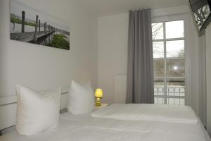 een slaapkamer met een wit bed en een raam bij Residenz am Balmer See - Kleine Auszeit - BS 21 mit Wellnessbereich in Balm