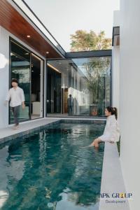 a woman sitting on the edge of a swimming pool in a house at H1 Pool Villa in Chiang Mai