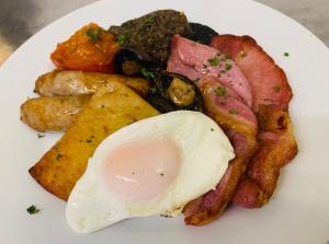 a plate of breakfast food with an egg and bacon at Navaar House Hotel in Penicuik
