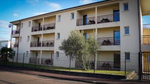 a white apartment building with a tree in front of it at Apparts Confort 87 in Limoges