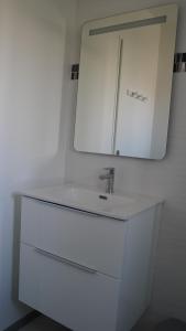 a white bathroom with a sink and a mirror at Apparts Confort 87 in Limoges