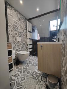 La salle de bains est pourvue d'une baignoire, de toilettes et d'un lavabo. dans l'établissement Appartement Le Baroque en duplex, à Mulhouse
