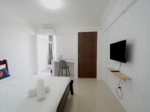 een witte slaapkamer met een bed en een televisie bij RoomQuest Suvarnabhumi Ladkrabang 42 in Bangkok