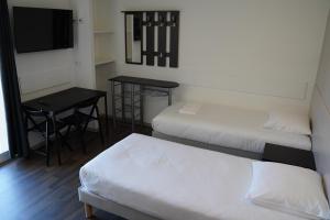 a room with two beds and a table and a television at Apparts Confort 87 in Limoges