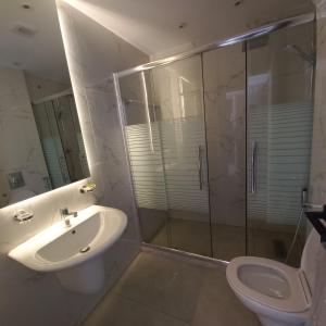 a bathroom with a sink and a shower and a toilet at Al Kawther Hotel Apartments in Amman