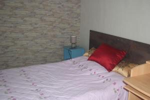 1 cama con almohada roja y pared de ladrillo en Maison entière 3 chambres, en Saint-Brevin-les-Pins