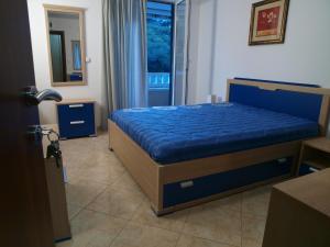 a bedroom with a bed with blue sheets and a window at Apartments Laništa Dragović in Petrovac na Moru