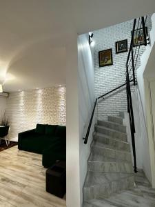 a living room with a staircase and a green couch at MG Mamaia North Villa in Mamaia Nord