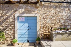 une porte bleue dans un bâtiment en pierre avec une chaise dans l'établissement Wine & Heritage - Johan i Matija in Grandići - Istrien, à Grandići