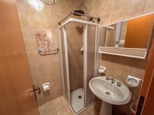 un piccolo bagno con doccia e lavandino di Monolocale ombrellone incluso a Lignano Sabbiadoro