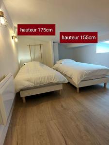 2 camas en una habitación con 2 letreros en la pared en Au cœur des vignes Moulin à Vent en La Chapelle-de-Guinchay