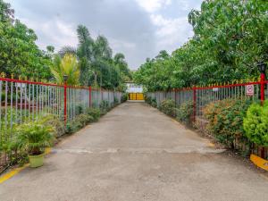 a long driveway with a red fence and trees at Natures Dreamland Holiday Homes, Igatpuri in Igatpuri