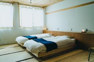 two beds in a room with white walls and windows at Hostel Saruya in Fujiyoshida