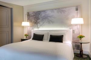 a bedroom with a white bed with two pillows at Renaissance Paris Nobel Tour Eiffel Hotel in Paris