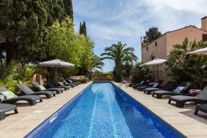 a swimming pool with chaise lounges and chairs at Masia Notari Casabona in Vilanova i la Geltrú