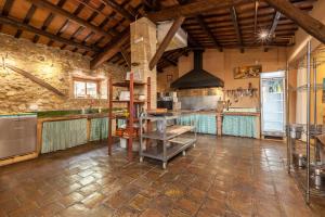 uma grande cozinha com tectos de madeira e uma parede de pedra em Masia Notari Casabona em Vilanova i la Geltrú