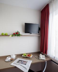 ヴュルツブルクにあるセントラル ホテル ガルニのデスク、テレビ、テーブル(食べ物付)が備わる客室です。