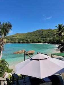 una sombrilla blanca sentada en una playa junto al océano en Villa Chez Batista, en Takamaka