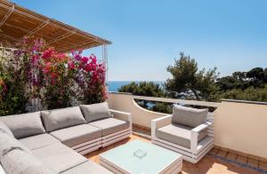 eine Terrasse mit einem Sofa, 2 Stühlen und Blumen in der Unterkunft Oliveto Capri apartments in Capri