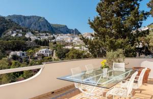 a glass table and chairs on a balcony with a view at Oliveto Capri apartments in Capri
