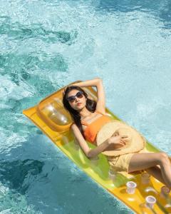 a woman laying on a raft in a swimming pool at Miami Hotel Bangkok - SHA Plus in Bangkok