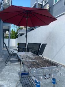 a table and chairs with a red umbrella at 110 Home Sleep Home Kuah Langkawi in Kuah