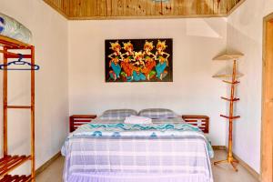 a bedroom with a bed and a painting on the wall at CABANAS Villa Del Mar in Farol de Santa Marta