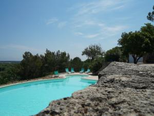 una piscina con sillas azules y árboles en Masseria Le Terrazze di Serranova, en Serranova