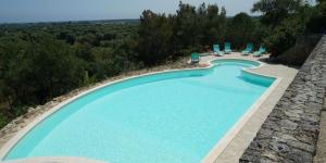 una vista sul soffitto di una piscina con sedie e acqua di Masseria Le Terrazze di Serranova a Serranova