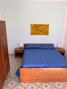 1 Schlafzimmer mit einem Bett mit blauer Decke und 2 Tischen in der Unterkunft Residenza Arrivabene Sicily in Valdina