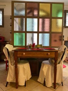 een tafel met stoelen in een kamer met ramen bij La casa degli zii in Ferrara
