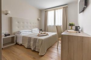 Cette chambre comprend un lit, une table et un bureau. dans l'établissement Hotel Catalunya, à Alghero