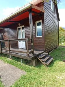 Ce chalet en bois dispose d'une terrasse couverte et de marches. dans l'établissement Chalet scandinave, à La Plaine-des-Palmistes