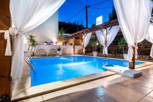 una piscina en un hotel con cortinas blancas en Kipos Resort, en Nea Peramos