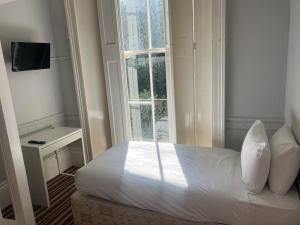 a small bedroom with a bed and a window at Palace Court Hotel in London