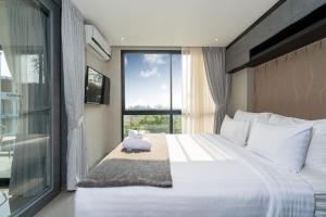 a bedroom with a large white bed and a window at Tropics Kamala 2BR Pool View Apartment CTG B705-6 in Kamala Beach +23 photos