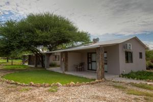 a small white house with a tree in front of it at Khoi-Khoi Guesthouse in Otavi