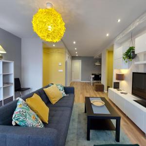 a living room with a blue couch and a yellow chandelier at Ático Ángela in Valladolid