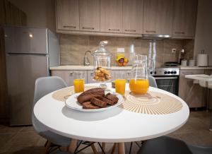 a white table with a plate of food and glasses of orange juice at Marialena Apartment by RentalsPro - Nea Moudania in Nea Moudania