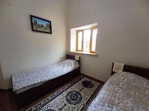 a small room with two beds and a window at Rassom Hostel in Samarkand