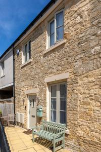 a green bench sitting outside of a stone building at Beautiful Honeycomb Cottage in heart of Cotswolds in Chipping Norton