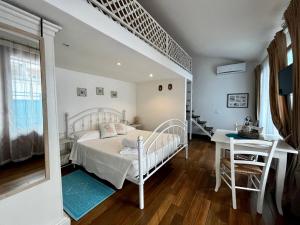 a white bedroom with a bed and a desk at Palmasera Bed & Breakfast in Cala Gonone