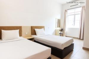 a hotel room with two beds and a window at De Harmony Stay in Malacca