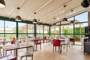 un restaurante con mesas, sillas y ventanas en Campanile Valence Nord - Bourg-Les-Valence, en Bourg-lès-Valence