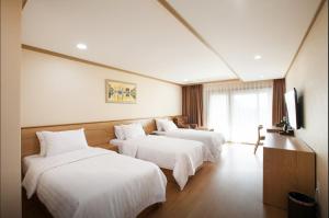 済州市にあるSH Nohyung Stayのホテルルーム ベッド3台(白いシーツ付)
