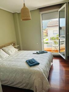- une chambre avec un lit et une grande fenêtre dans l'établissement Playa de Berria - Precioso Apartamento con piscina y Garaje incluido, à Santoña